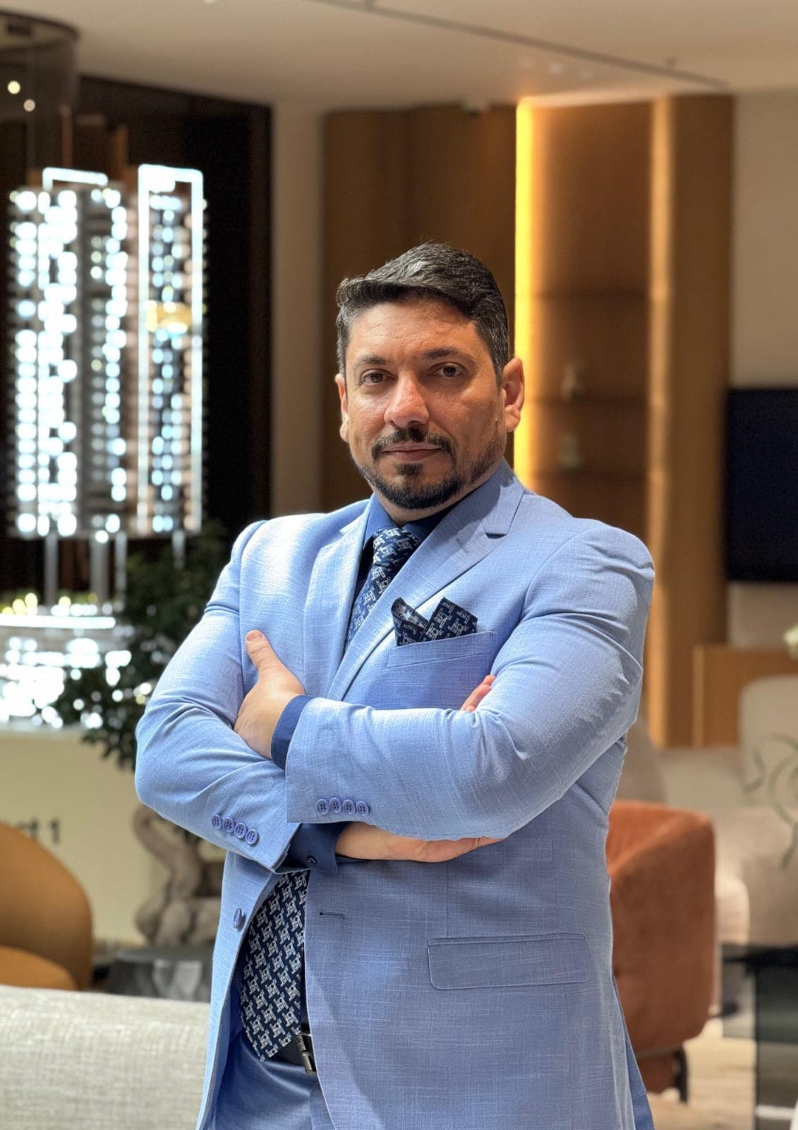 وئام النجار عاقدًا ذراعيه في صالة مبيعات عقارية في دبي